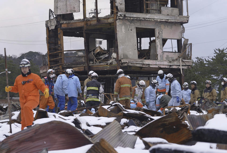 Firefighters search the snow-covered rubble at a marketplace after a large fire in the earthquake-hit city, Wajima, Ishikawa prefecture, Monday, Jan. 8, 2024. Thousands of people made homeless overnight are living in weariness and uncertainty on the western coast of Japan a week after powerful earthquakes hit the region. (Kyodo News via AP)