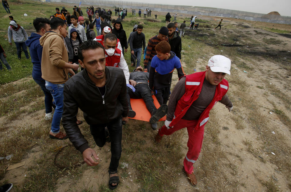 Medics and protester evacuate a wounded youth, who was shot by Israeli troops from near the fence of the Gaza Strip's border with Israel, while marking first anniversary of Gaza border protests east of Gaza City, Saturday, March 30, 2019. Tens of thousands of Palestinians on Saturday gathered at rallying points near the Israeli border to mark the first anniversary of weekly protests in the Gaza Strip, as Israeli troops fired tear gas and opened fire at small crowds of activists who approached the border fence. (AP Photo/Abdel kareem Hana)