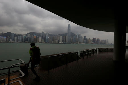 A man takes a photo at a waterfront facing the island skyline as Typhoon Haima approaches in Hong Kong, China, October 21, 2016. REUTERS/Bobby Yip