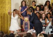 U.S. President Barack Obama hugs UConn women's basketball coach Geno Auriemma as team star Stefanie Dolson (L) falls off the stage in the background during a ceremony honoring the NCAA basketball champion University of Connecticut Huskies men's and women's basketball teams in the East Room of the White House in Washington, June 9, 2014. Dolson was unhurt in the fall. REUTERS/Jim Bourg (UNITED STATES - Tags: POLITICS SPORT BASKETBALL TPX IMAGES OF THE DAY)