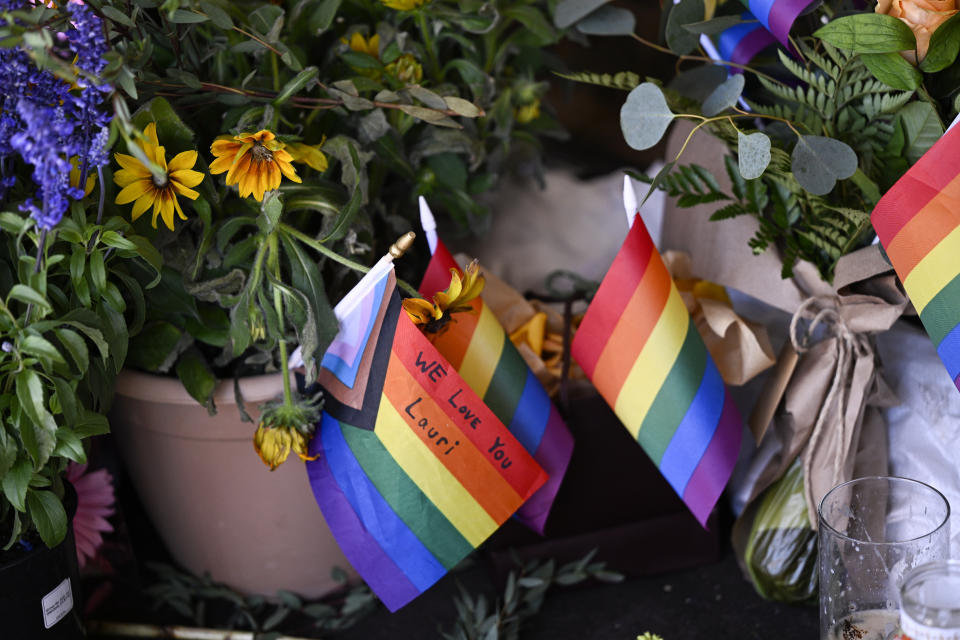 Rows of flowers and pride flags cover the Mag.Pi storefront window as a memorial for late Cedar Glen community member and store owner Laura Ann “Lauri” Carleton on Tuesday, Aug. 22, 2023, in Cedar Glen. Carleton was shot outside of her clothing store on Friday, Aug. 18, by a man who had ripped down an LGBTQ+ Pride flag outside the business and shouted homophobic slurs at her. (Anjali Sharif-Paul/The Orange County Register via AP)