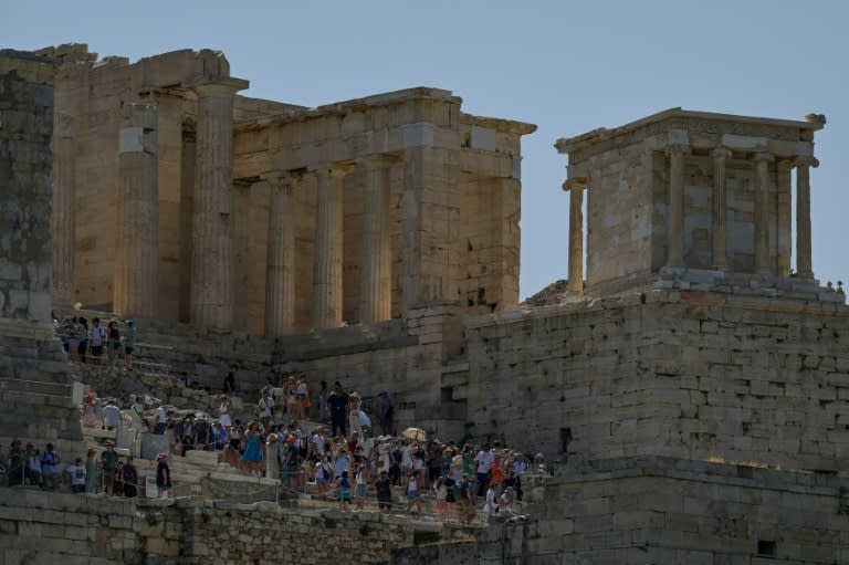 Unos turistas, sentados en las eslaceras de la colina de la Acrópolis, en Atenas, en un caluroso 12 de junio de 2024 (Stringer)