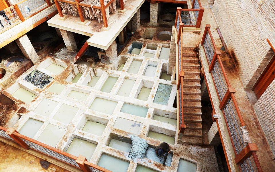 <p>Several tanneries dot the Fez medina. The most well-known is the Chouara Tannery, which dates back almost one thousand years. Pictured here, tanners soak cow, goat, sheep, and camel skins in vats. Some contain mixtures of cow urine to clean the skins, while others contain pigeon dung to soften the hides. To soften the hides, the tanners stand in the vats to knead the skins with their feet.</p>