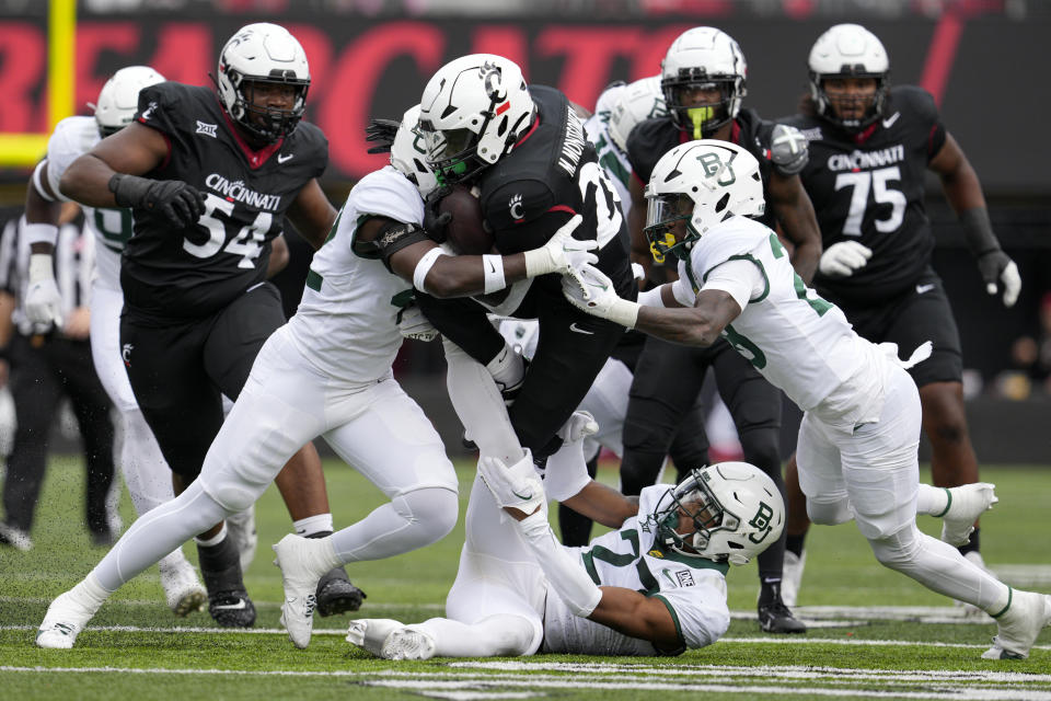 Cincinnati running back Myles Montgomery, center, is tackled by Baylor's Tevin Williams III (27), Reggie Bush, center left, and Devyn Bobby during the first half of an NCAA college football game, Saturday, Oct. 21, 2023, in Cincinnati. (AP Photo/Jeff Dean)