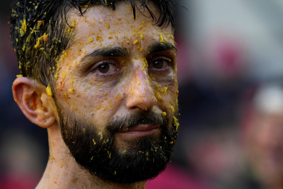 A man reacts as his face is covered with orange juice during the 'Battle of the Oranges" where people pelt each other with oranges as part of Carnival celebrations in the northern Italian Piedmont town of Ivrea, Italy, Tuesday, Feb. 13, 2024. (AP Photo/Antonio Calanni)