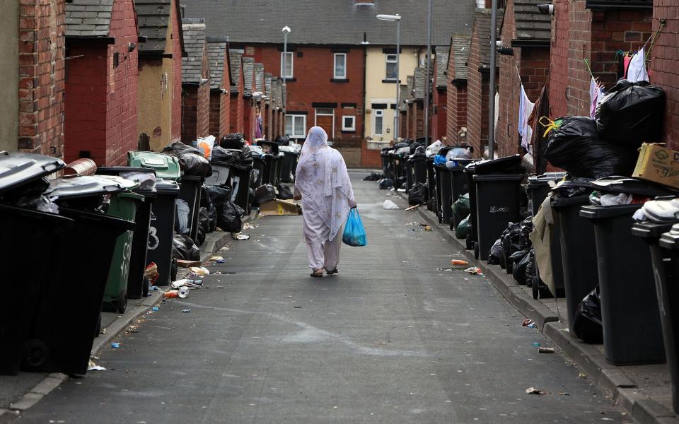 A resident walks past overflowing refuse bins in the Beeston area of Leeds - Christopher Furlong/Getty News