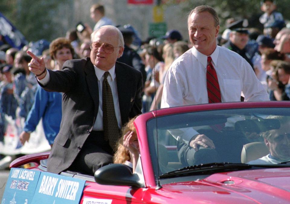 Dallas Cowboys head football coach Barry Switzer waves to the supportive crowd as he rides with Cowboys Player Personnel Director Larry Lacewell, left, in the Cowboys' Super Bowl victory parade in through Dallas- on Feb. 7, 1996.
