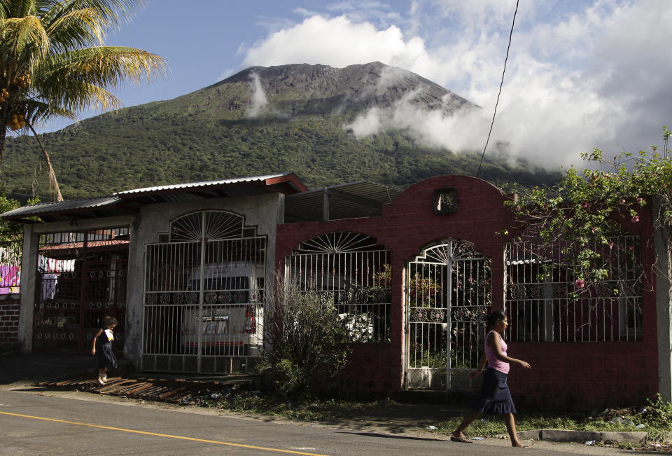 People walk in Chinameca near to the Chaparrastique volcano, El Salvador, Monday, Nov. 28, 2022. Authorities in El Salvador are warning residents near the Chaparrastique in the eastern part of the country to be alert as the volcano has shown signs of increased activity. (AP Photo/Salvador Melendez)