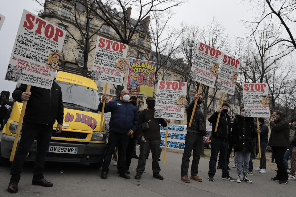 Circus workers holds posters during a protest near the National Assembly, Tuesday, Jan.26, 2021. French lawmakers start debating Tuesday a bill that would ban using wild animals in traveling circuses and keeping dolphins and whales in captivity in marine parks, amid other measures to better protect animal welfare. Circus workers stage a protest outside the National Assembly to denounce what they consider "a mistake." (AP Photo/Lewis Joly)