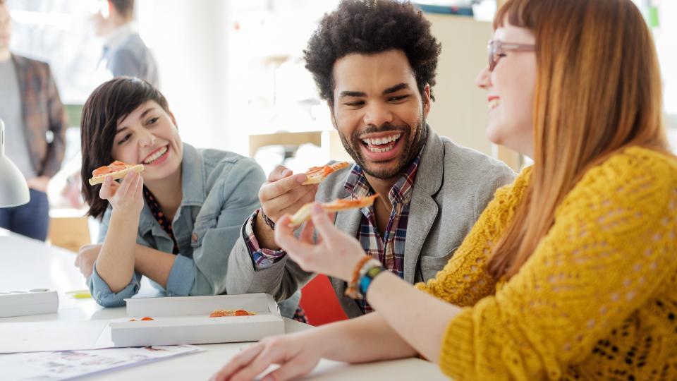 Group of young entrepreneurs eating lunch at their desk.