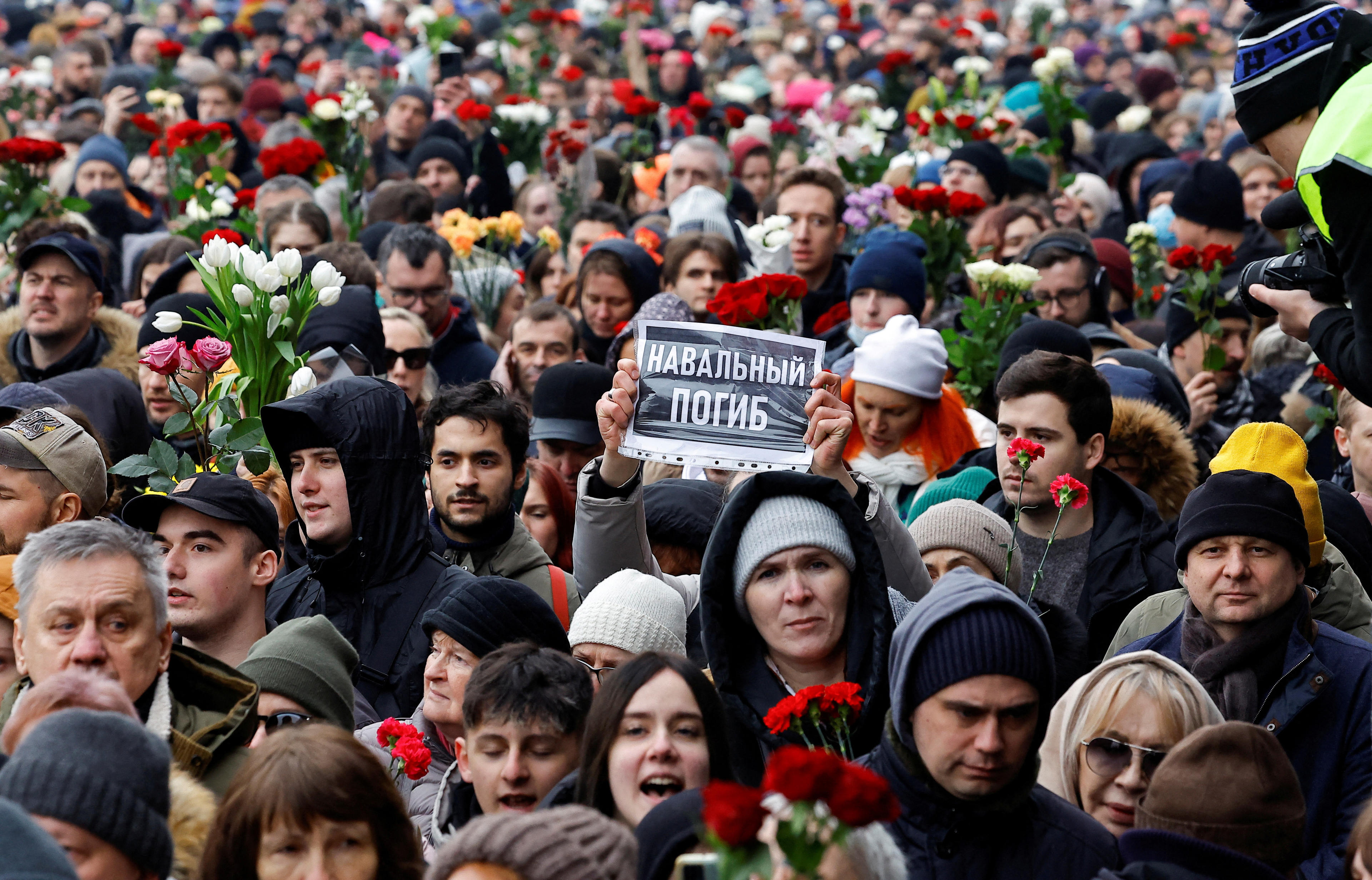 Dozens of Alexei Navalny’s mourners, some carrying bouquets of flowers, walk from the church to the cemetery.