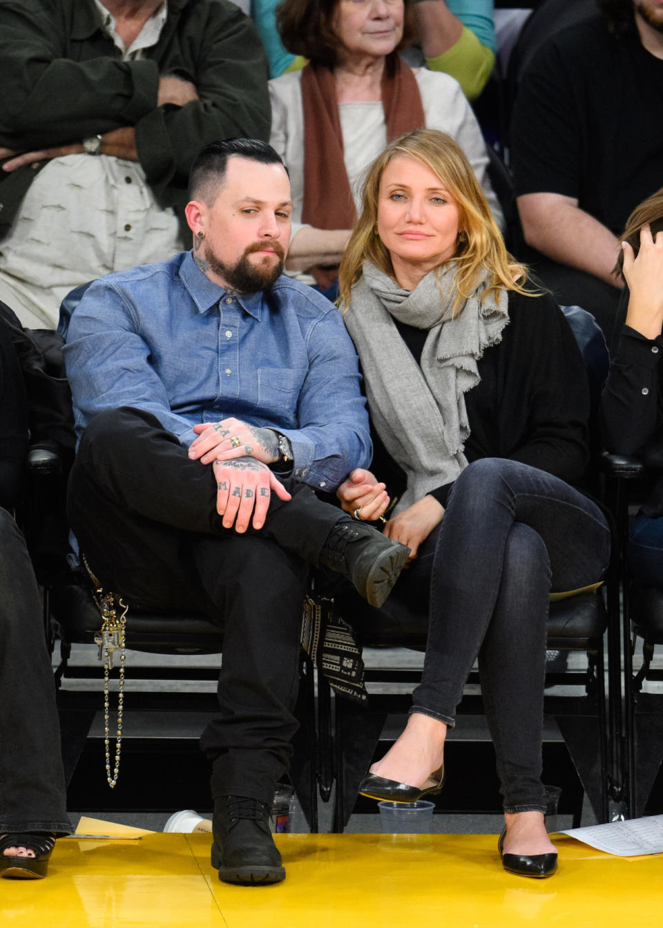 Cameron Diaz sat courtside at a Lakers game wearing a gray scarf, black sweater, jeans, and flats. Her chic look was on full display after being caught on the Jumbrotron’s kiss cam planting a smooch on her new husband, Benji Madden, who went for more business casual than rocker as per usual.