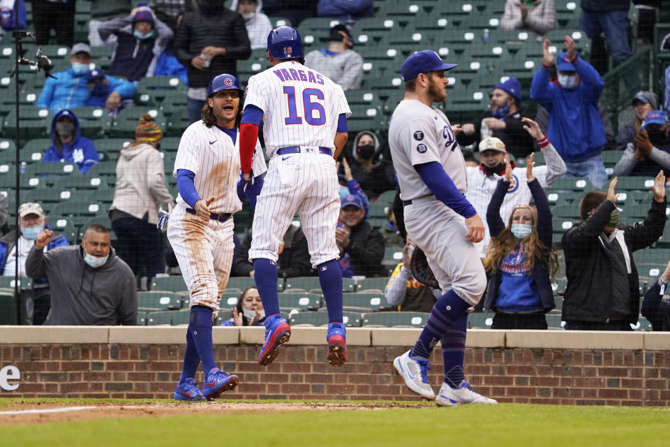 Chicago Cubs' Ildemaro Vargas, center, and Jake Marisnick, left, celebrate as they both scored on a wild pitch as Los Angeles Dodgers first baseman Max Muncy, right, stands nearby during the third inning of the first baseball game of a doubleheader Tuesday, May, 4, 2021, in Chicago. (AP Photo/David Banks)