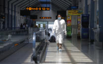 A Sri Lankan airport worker in protective suit walks inside a terminal at the Katunayake International Airport in Colombo, Sri Lanka, Wednesday, Jan. 20, 2021. Sri Lanka's tourism minister said that the airports in the country will be reopened for tourists according to health guidelines from Jan.21. (AP Photo/Eranga Jayawardena)