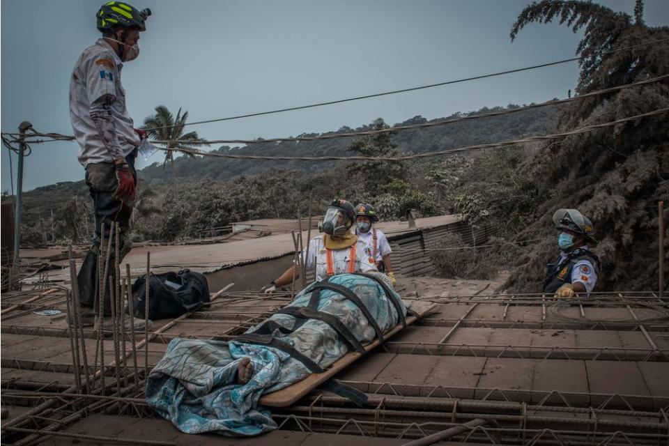 Rescuers recover a body among the ruins of the village of San Miguel Los Lotes, near the Guatemalan city of Escuintla, on June 4.
