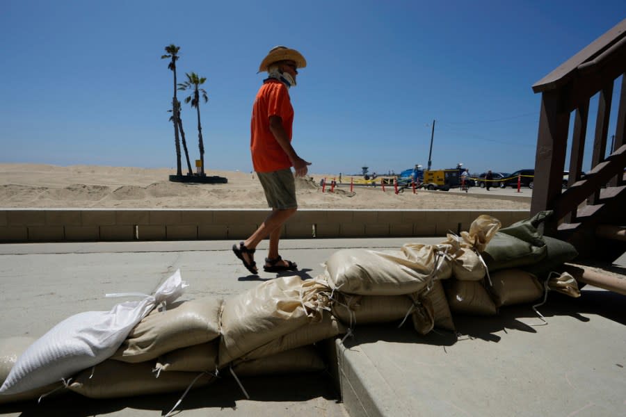 Seal Beach resident Tom Ostrom, walks past a home protected with sandbags in Seal Beach, Calif., Friday, Aug. 18, 2023. (AP Photo/Damian Dovarganes)