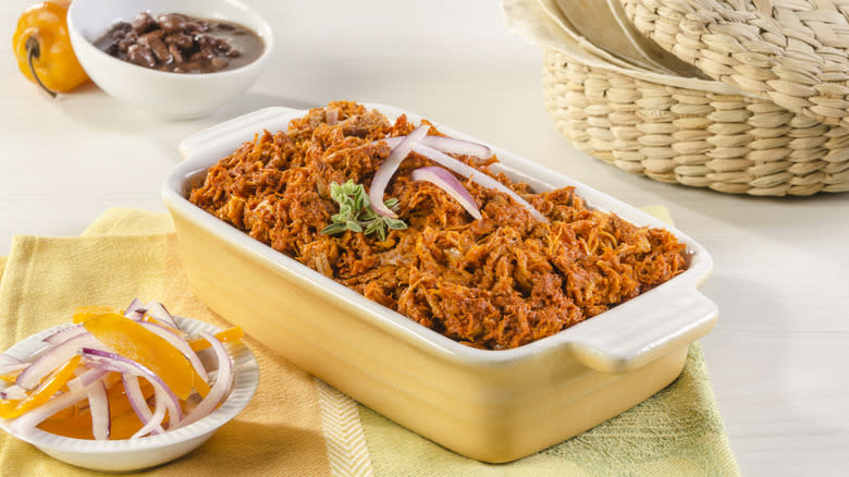 Cochinita pibil in serving dish with sides