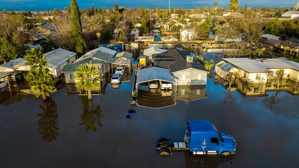 Floodwaters surround homes and vehicles on Jan. 10, 2023, in the Planada community of Merced County, California