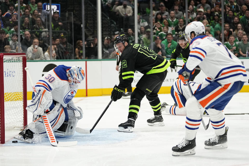 Dallas Stars center Radek Faksa (12) takes a shot as Edmonton Oilers' Calvin Pickard (30) and Vincent Desharnais (73) defend the net in the first period of an NHL hockey game, Wednesday, April 3, 2024, in Dallas. (AP Photo/Tony Gutierrez)