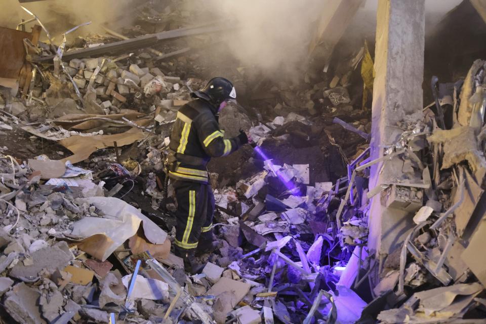 A Donetsk's emergency employee works at a site of a shopping center destroyed after what Russian officials in Donetsk said it was a shelling by Ukrainian forces, in Donetsk, in Russian-controlled Donetsk region, eastern Ukraine, Monday, Jan. 16, 2023. (AP Photo/Alexei Alexandrov)