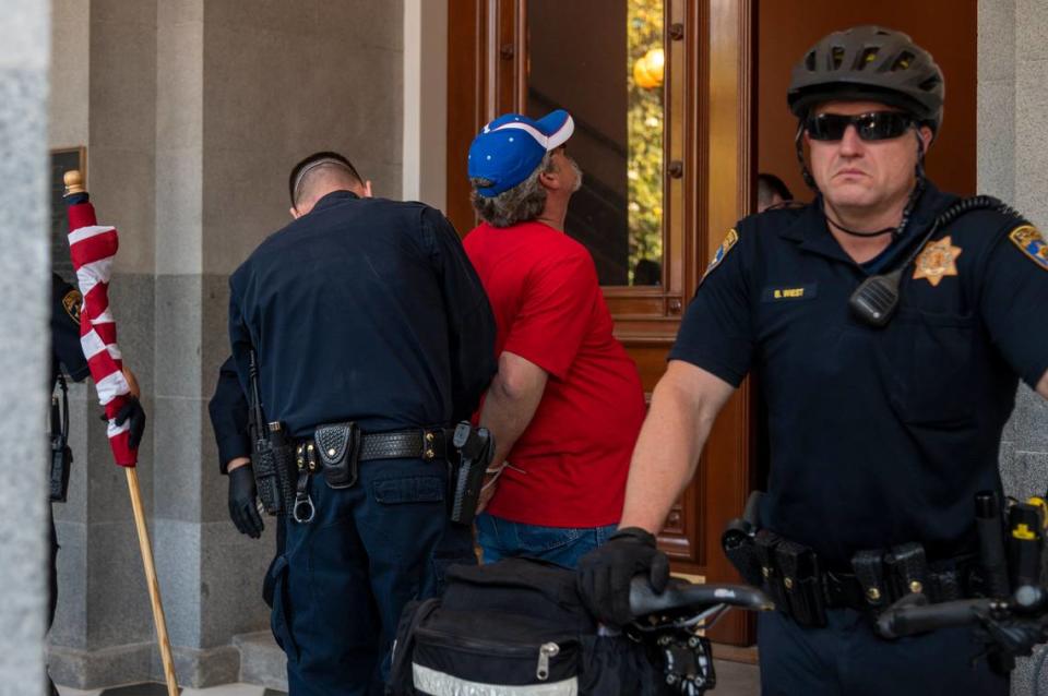 A protester is detained at the Capitol in Sacramento on Friday, May 1, 2020, while demonstrating against Gov. Gavins Newsom stay-at-home order to slow the spread of the coronavirus.