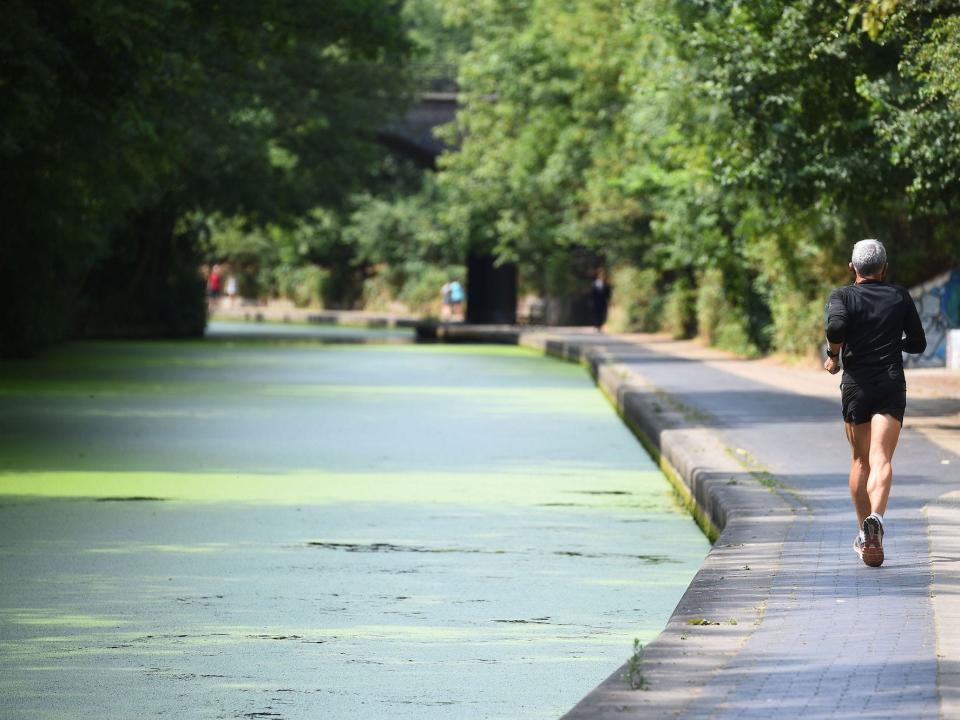 A man jogs next to a canal.