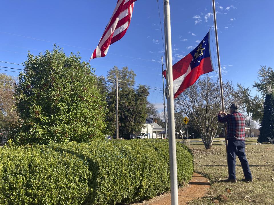 Lee Johnson, an employee of the town of Plains, Ga., lowers the American and Georgia state flags on the morning Monday, Nov. 20, 2023, to recognize the death of Rosalynn Carter. The former U.S. first lady died Sunday at the age of 96. She and former President Jimmy Carter were both born, married and lived most of their lives in their hometown of about 600 people. (AP Photo/Bill Barrow)