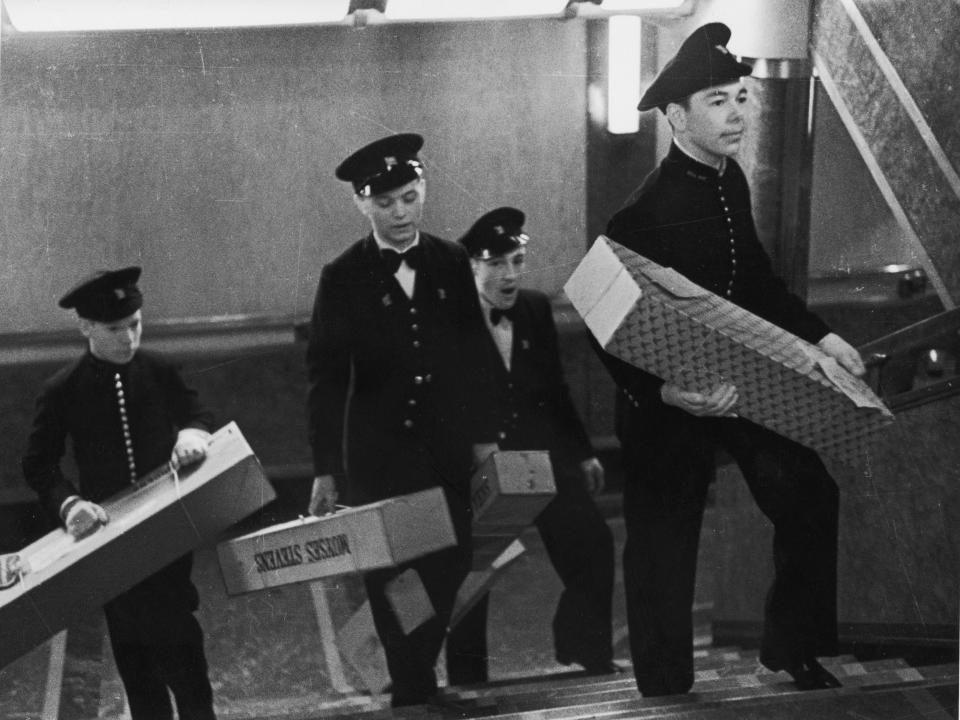 Bellhops bring boxes of flowers to passengers on the Cunard White Star liner Queen Mary.