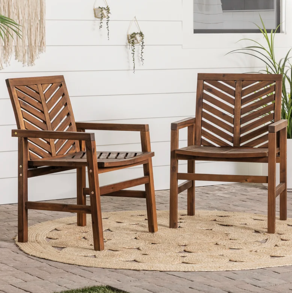 Harbison Acacia Patio Dining Armchair (Set of 2) in brown wood on rattan carpet (Photo via Wayfair)