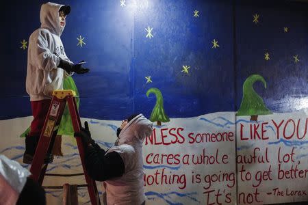 Volunteers Elliot Bailey (L) and Maria Whelan paint a mural on boarded-up businesses before a third night of protests in reaction to the grand jury verdict in the Michael Brown shooting in Ferguson, Missouri November 26, 2014. REUTERS/Lucas Jackson