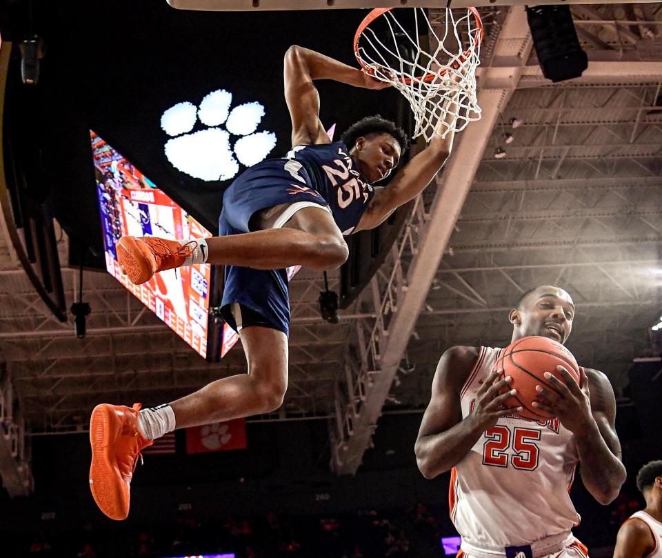 Virginia guard Trey Murphy III hangs on the rim after dunking near Clemson's Aamir Simms during an ACC game last season.