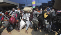 People wearing masks as a precaution against the coronavirus stand in queues to board trains at Lokmanya Tilak Terminus in Mumbai, India, Wednesday, April 14, 2021. India is experiencing its worst pandemic surge, with average daily infections exceeding 143,000 over the past week. (AP Photo/Rafiq Maqbool)