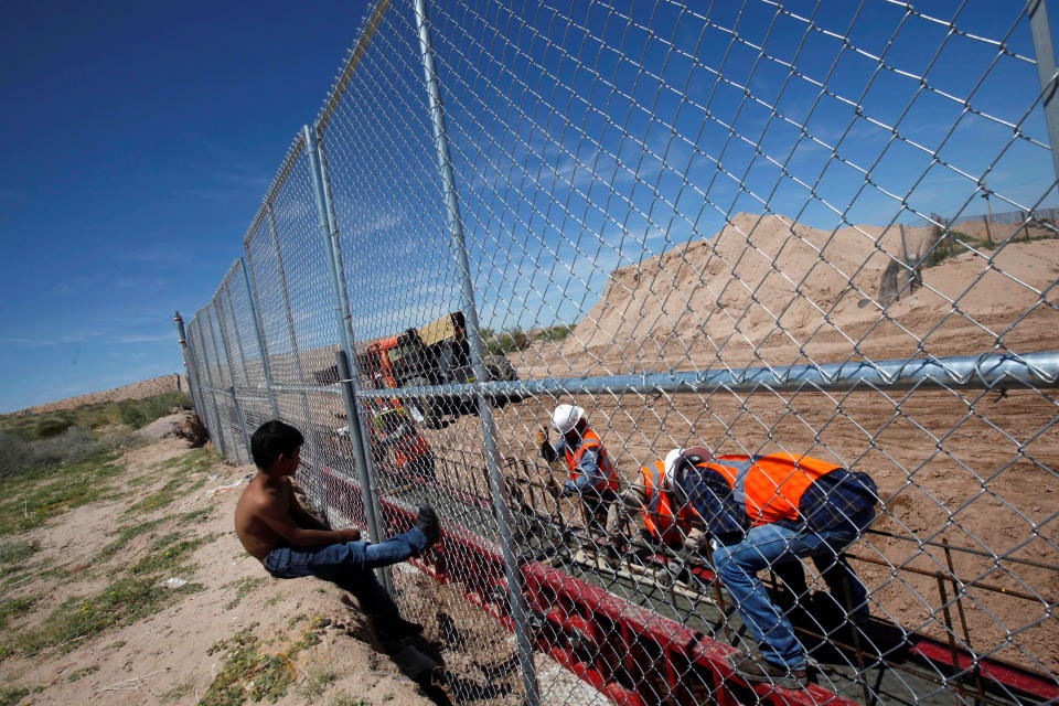 A boy looks as U.S. workers build a section of the U.S.-Mexico border wall.
