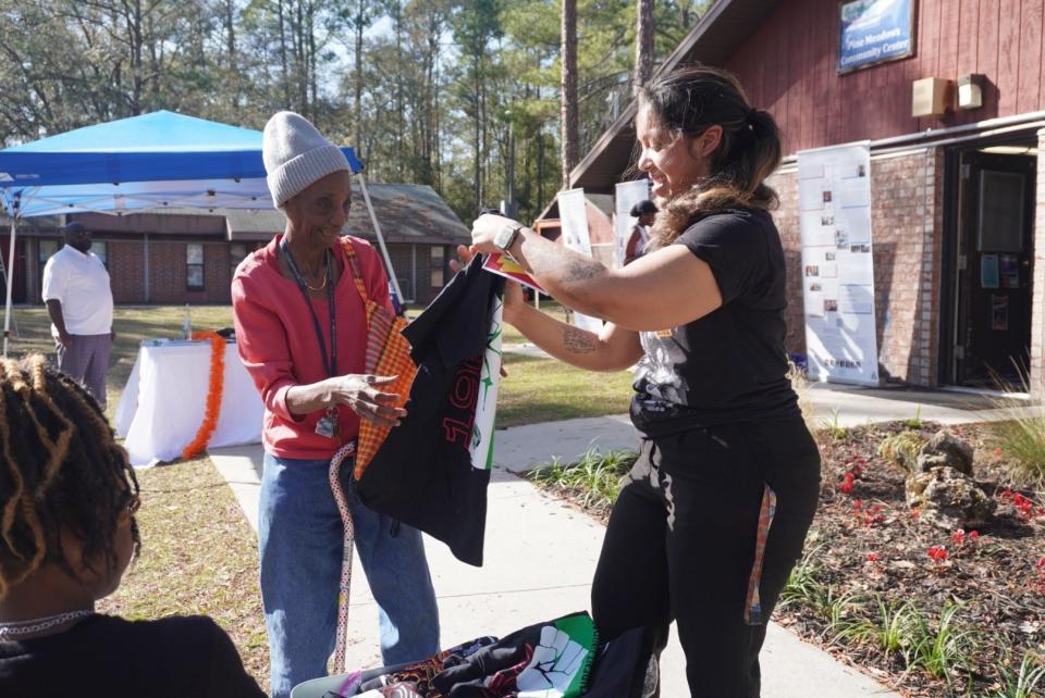 Nidia Volmar, right, a social service intern at the Gainesville Housing Authority hands a shirt to a woman at GHA's “Revitalizing Our Roots" Black History Month event on Saturday in east Gainesville.