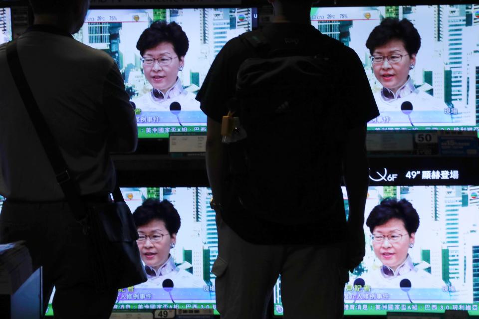 Residents watch a broadcast of Chief Executive Carrie Lam speaking at a press conference held in Hong Kong on Saturday, June 15, 2019. Lam said she will suspend a proposed extradition bill indefinitely in response to widespread public unhappiness over the measure, which would enable authorities to send some suspects to stand trial in mainland courts.