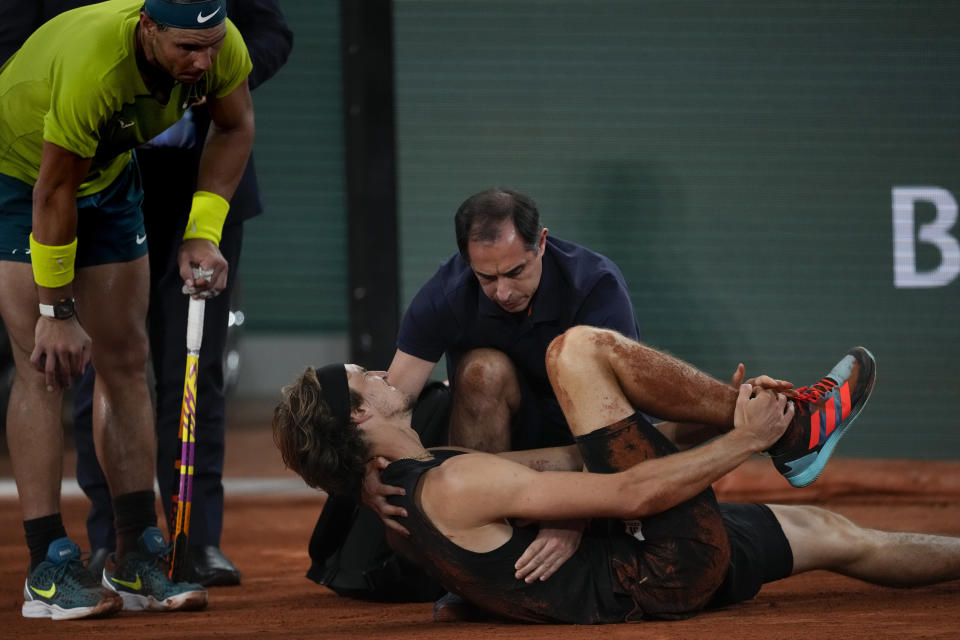 Germany's Alexander Zverev holds his right ankle after twisting it, as Spain's Rafael Nadal, left, looks on during their semifinal match at the French Open tennis tournament in Roland Garros stadium in Paris, France, Friday, June 3, 2022. (AP Photo/Christophe Ena)