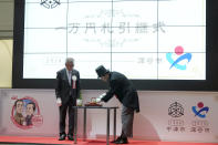 Fukaya Mayor Susumu Kojima, right, Nakatsu Mayor Masanori Okuzuka, left, perform a ceremony during the "10,000 Yen Bill Handover Ceremony" at Tokyo Stock Exchange Wednesday, July 3, 2024, in Tokyo. New 10000 yen bill featuring a portrait of Shibusawa Eiichi, the "father of Japanese capitalism.", from Fukaya city. Nakatsu city is where Yukichi Fukuzawa, a figure of previous 10000 yen bill, was from. (AP Photo/Eugene Hoshiko)