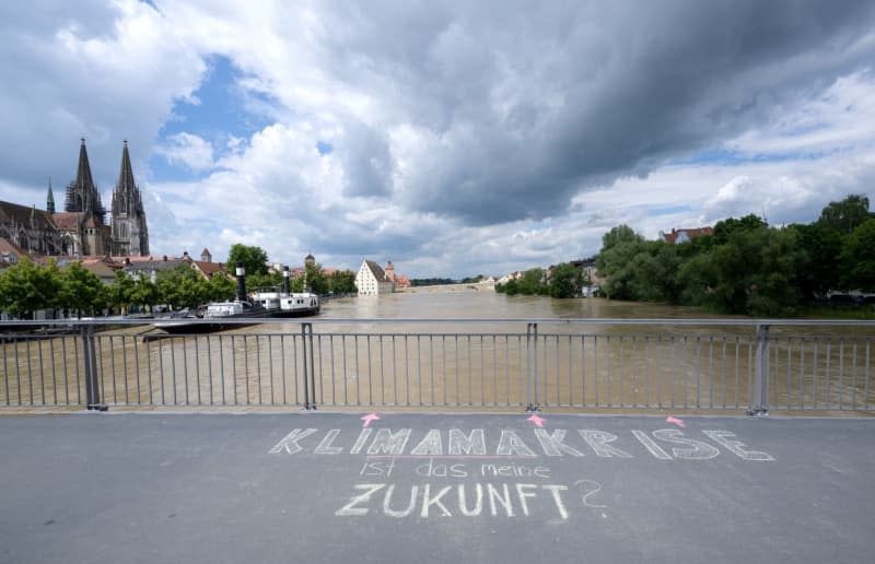 The words "Climate crisis: is this my future?" can be read on a bridge over the Danube in the old town.  The cathedral and the stone bridge can be seen in the background.  Emergency workers in Bavaria have been fighting the flooding and its consequences for days.  Sven Hoppe/dpa