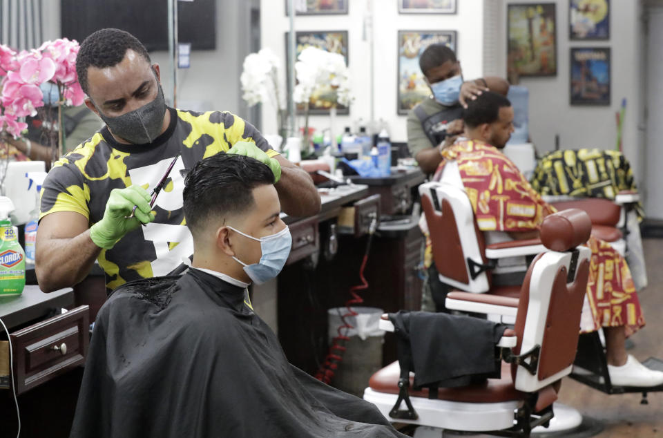 Barbers in  Florida wear masks to protect against the coronavirus while at work on May 21. Personal grooming shops were allowed to open the day before, during a phased reopening of certain businesses in Miami-Dade County. (Photo: Wilfredo Lee/AP)