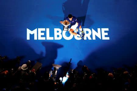 Serbia's Novak Djokovic sits on the court as he celebrates with the men's singles trophy after winning his final match against Britain's Andy Murray at the Australian Open tennis tournament at Melbourne Park, Australia, January 31, 2016. REUTERS/Jason Reed