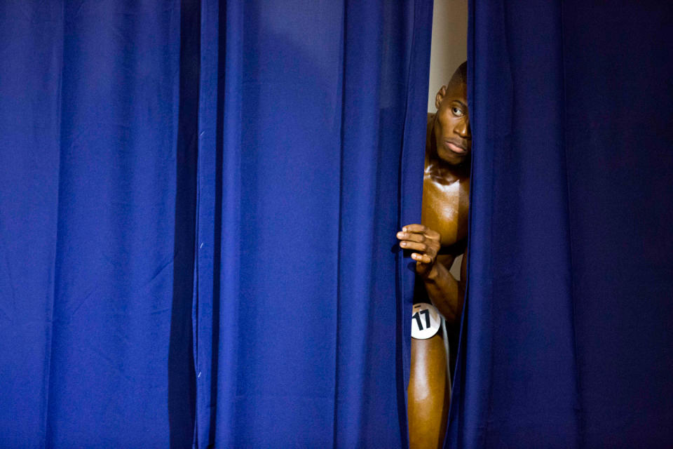 <p>In Port-au-Prince lugt ein Kraftsportler hinter einem Vorhang hervor, um seine Kontrahenten zu beobachten. Die Haiti Bodybuilding Classics ist die erste Veranstaltung dieser Art. Sie soll die Beziehungen zum Nachbarland, der Dominikanischen Republik, stabilisieren. (Bild: AP Photo) </p>