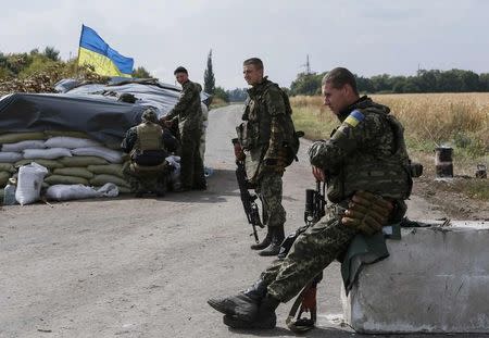 Members of the Ukrainian national guard are seen at a checkpoint nearby the town of Slavyanoserbsk, in Luhansk region September 10, 2014. Ukraine's president said on Wednesday Russia had removed the bulk of its forces from his country, raising hopes for a peace drive now underway after five months of conflict in which more than 3,000 people have been killed. REUTERS/Gleb Garanich