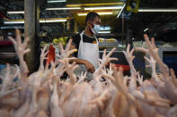 A poultry vendor wearing a face mask to help curb the spread of the coronavirus prepares birds at a wet market in downtown Kuala Lumpur, Malaysia, Friday, April 24, 2020. Malaysia, along with neighboring Singapore and Brunei, has banned popular Ramadan bazaars where food, drinks and clothing are sold in congested open-air markets or road-side stalls. The bazaars are a source of key income for many small traders, some who have shifted their businesses online. (AP Photo/Vincent Thian)