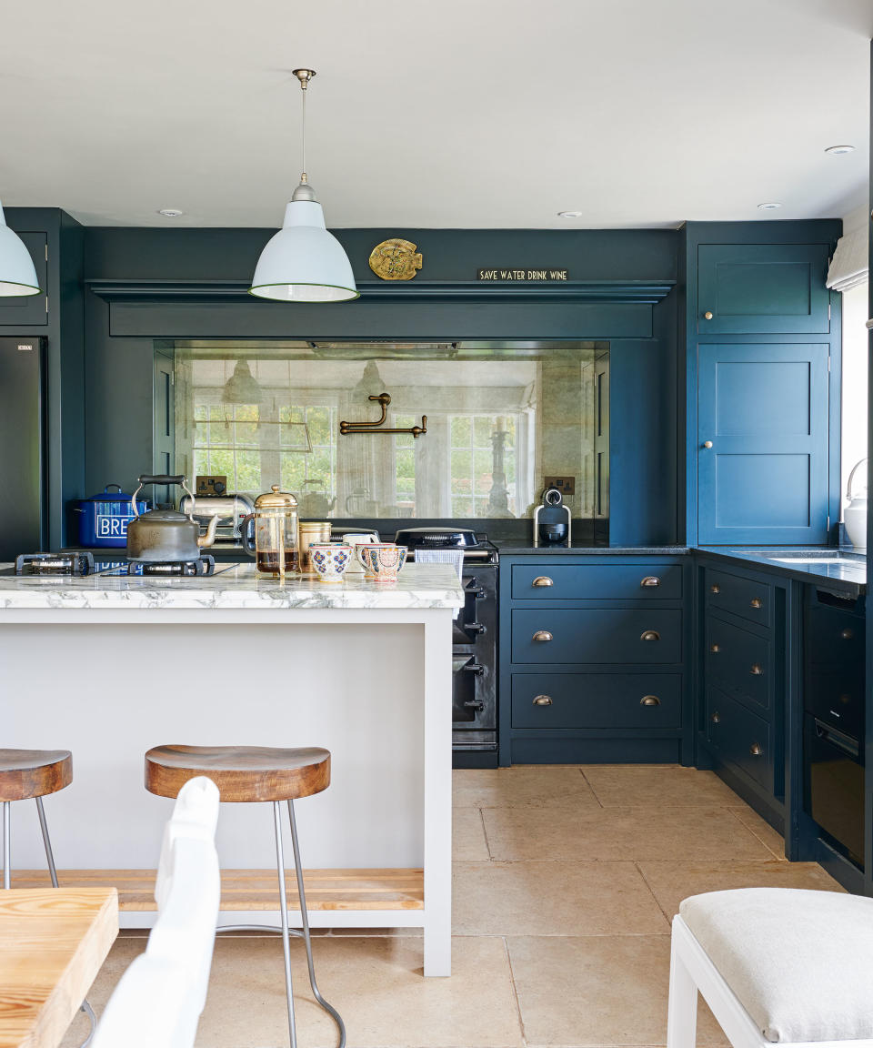 Kitchen island ideas shown here in white in the middle of a deep blue painted kitchen scheme.