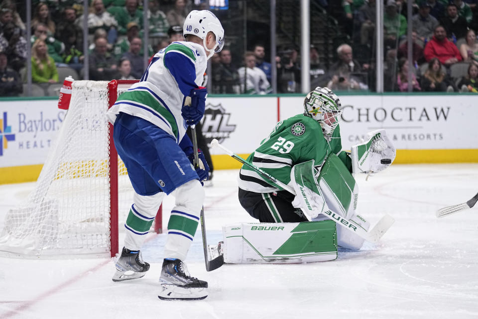 Dallas Stars goaltender Jake Oettinger (29) reaches out to glove a shot while under pressure from Vancouver Canucks center Elias Pettersson (40) in the second period of an NHL hockey game, Monday, Feb. 27, 2023, in Dallas. (AP Photo/Tony Gutierrez)