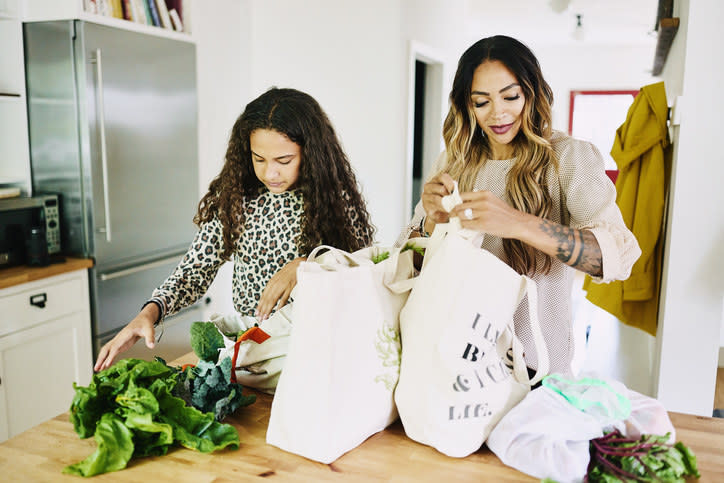 A mother and daughter taking groceries out of bags