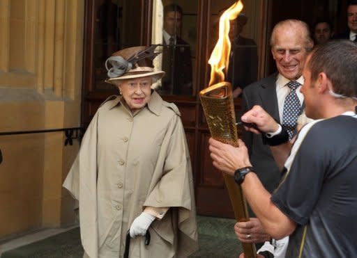 Britain's Queen Elizabeth II (L) and her husband Prince Philip look at the Olympic Flame at Windsor Castle in London on July 10. The 86-year-old monarch will officially open the Games at Friday's Olympic opening ceremony