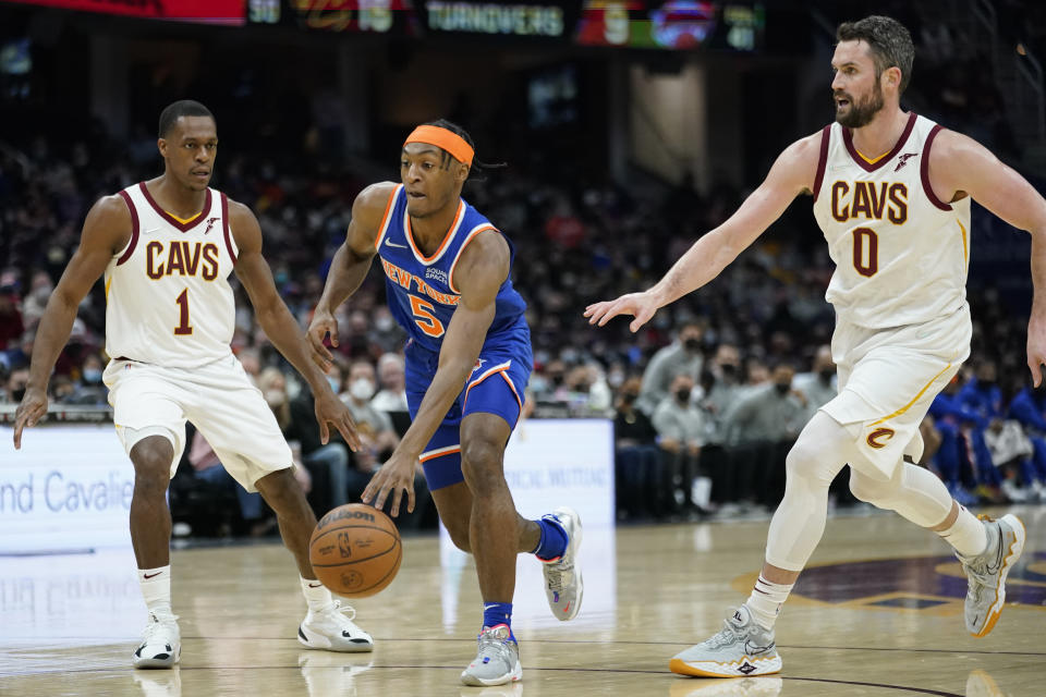 New York Knicks' Immanuel Quickley (5) drives between Cleveland Cavaliers' Rajon Rondo (1) and Kevin Love (0) in the second half of an NBA basketball game, Monday, Jan. 24, 2022, in Cleveland. (AP Photo/Tony Dejak)