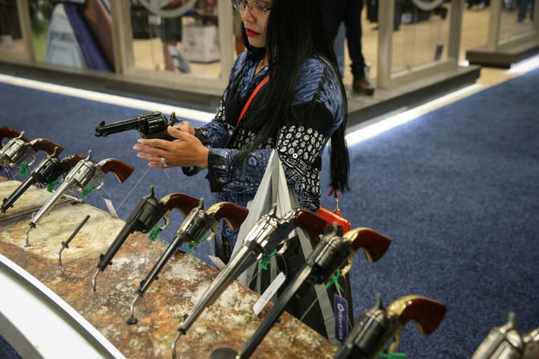 A woman inspects a firearm at the NRA convention