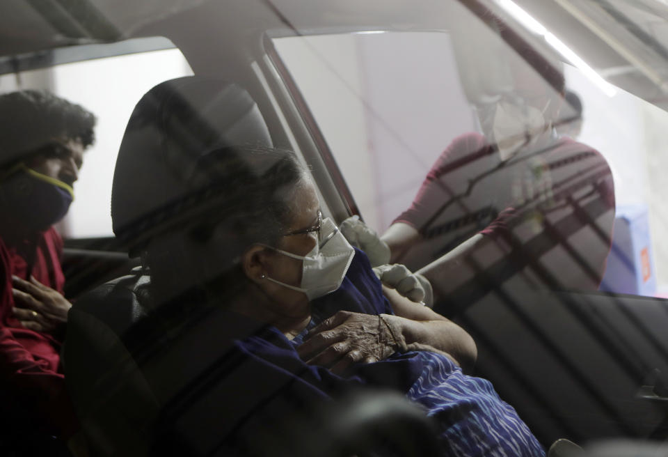 A woman receives a vaccine for COVID-19 in her car at a drive-in vaccination centre in Mumbai, India, Tuesday, May 4, 2021. COVID-19 infections and deaths are mounting with alarming speed in India with no end in sight to the crisis. (AP Photo/Rajanish Kakade)